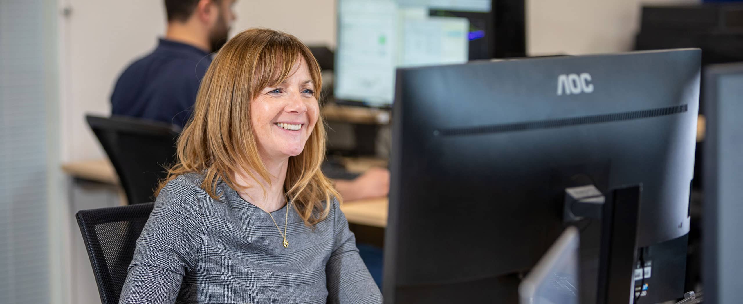 Woman sat at desk looking at a PC screen