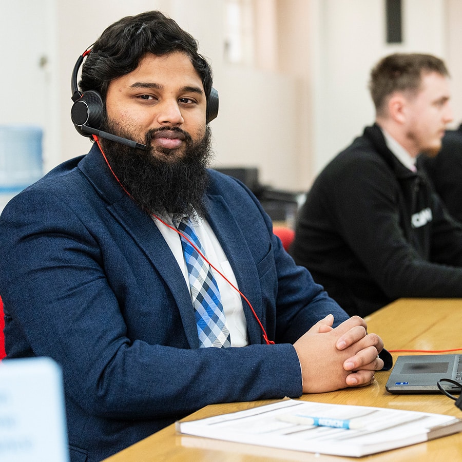 Man at a desk wearing a suit and a headset