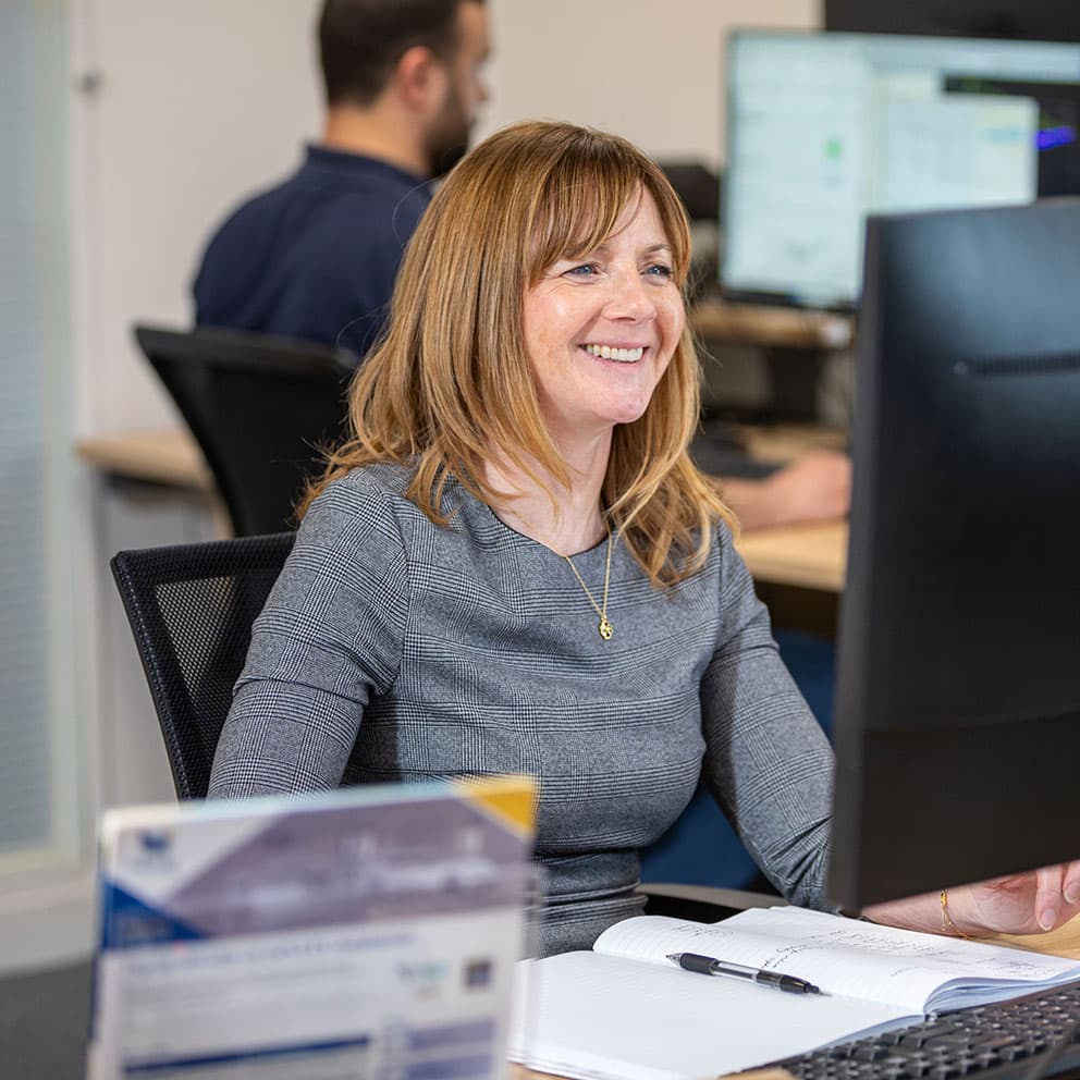 Woman sat at desk looking at a PC screen