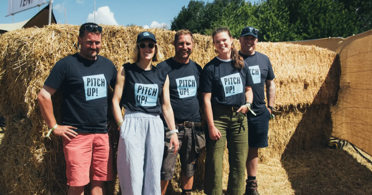 A group of farmers stand in front of hay bales wearing Pitch Up t-shirts