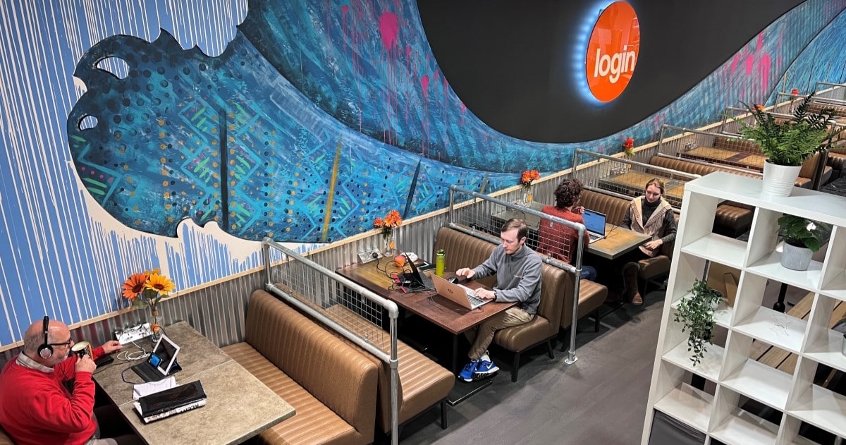 Aerial image of a coworking space. People are sat in booths working on laptops while drinking coffee.