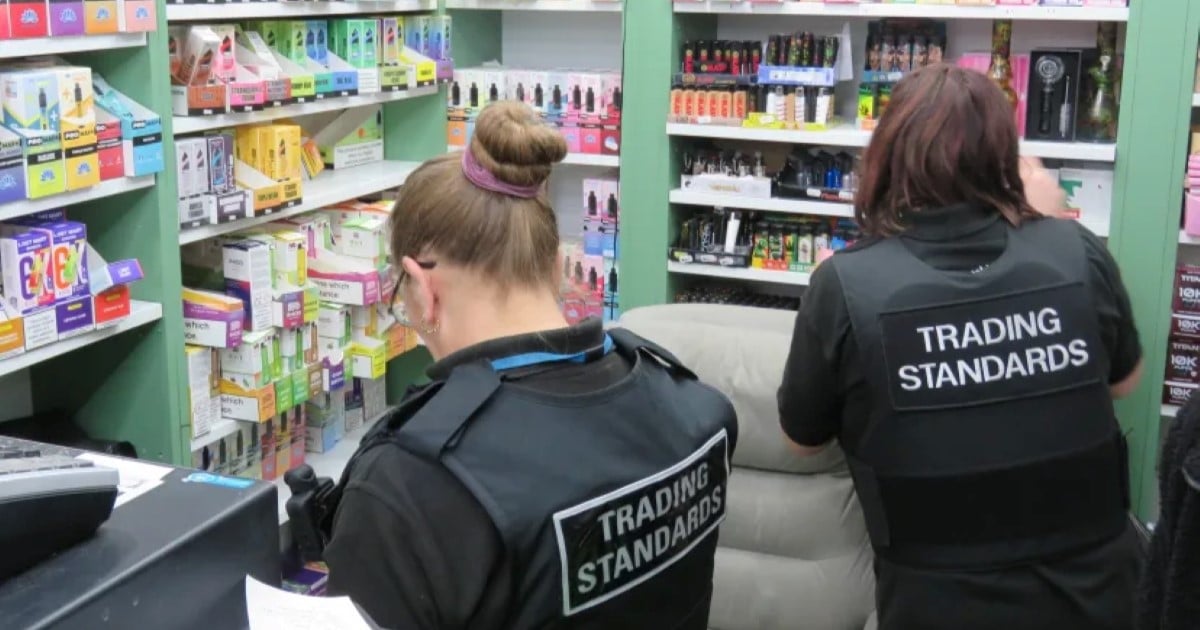 Two people in black Trading Standards jackets look at goods in shops as part of Operation Machinize