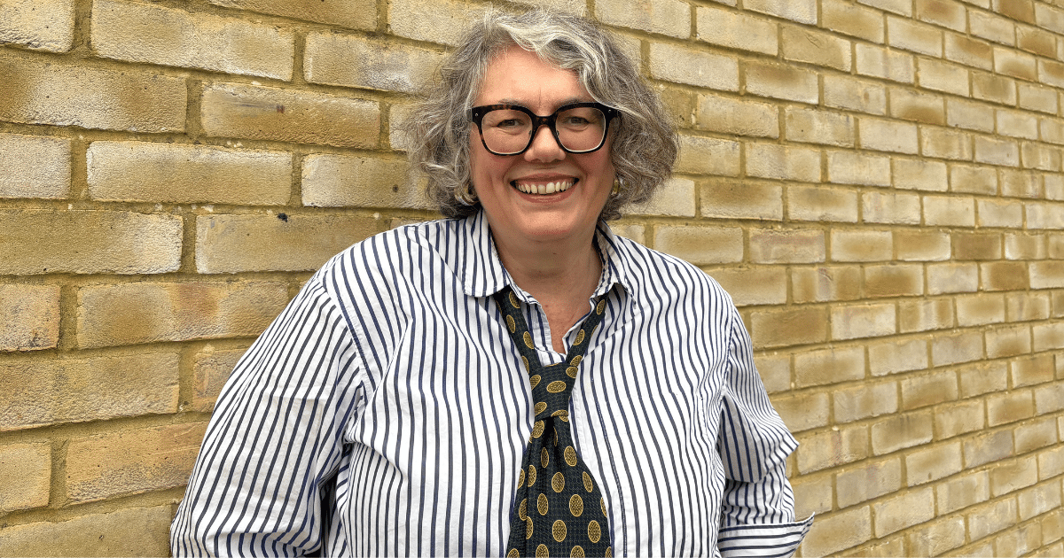 Renee is standing in front of a brick wall, wearing a shirt and tie and dark framed glasses smiling at the camera. Renee's roundup of grants and funding.