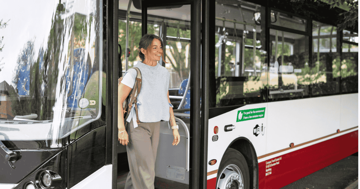 Active travel - woman steps off a bus on her commute to work ~ Business Surrey