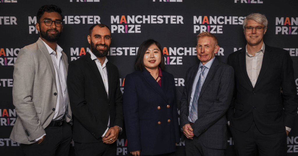 A group of employees from BiofuelAI in Surrey pose in front of a backdrop for the Manchester Prize
