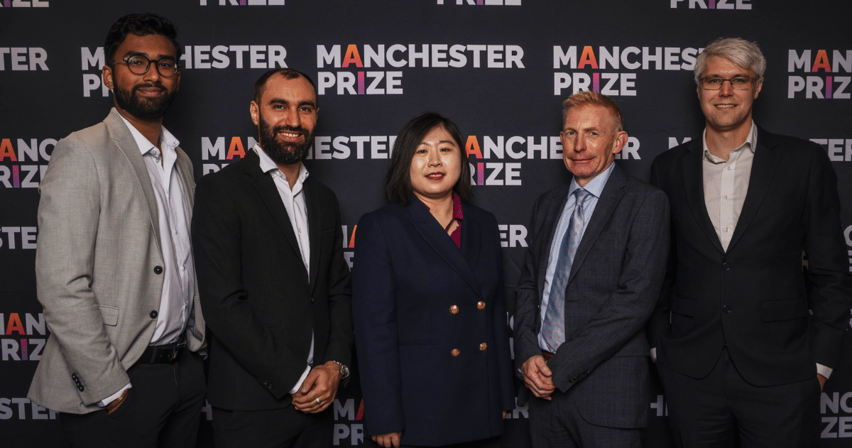 A group of employees from BiofuelAI in Surrey pose in front of a backdrop for the Manchester Prize