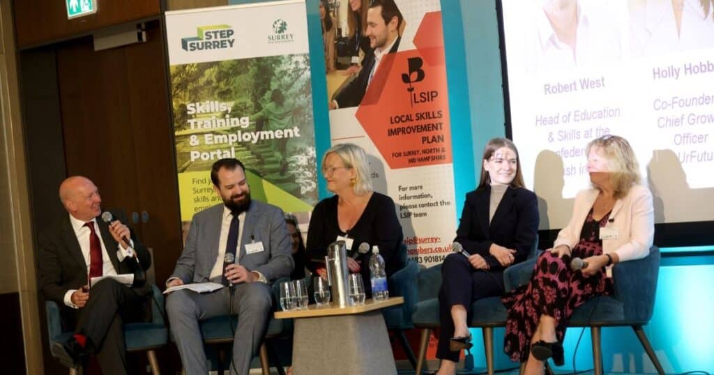 Five people in suits sit in chairs as part of a panel discussion. Behind them are banners for the Surrey Local Skills Improvement Plan and STEP Surrey.