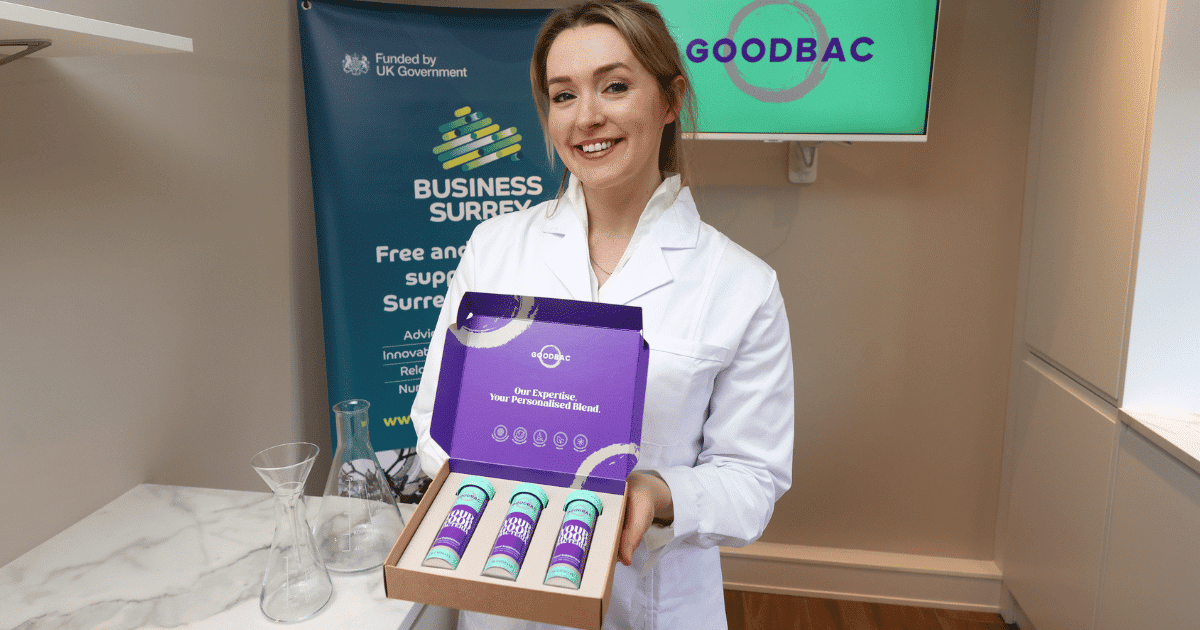 woman in lab coat holds out a box of tablet containers | Goodbac | Business Surrey | personalised probiotics business Surrey