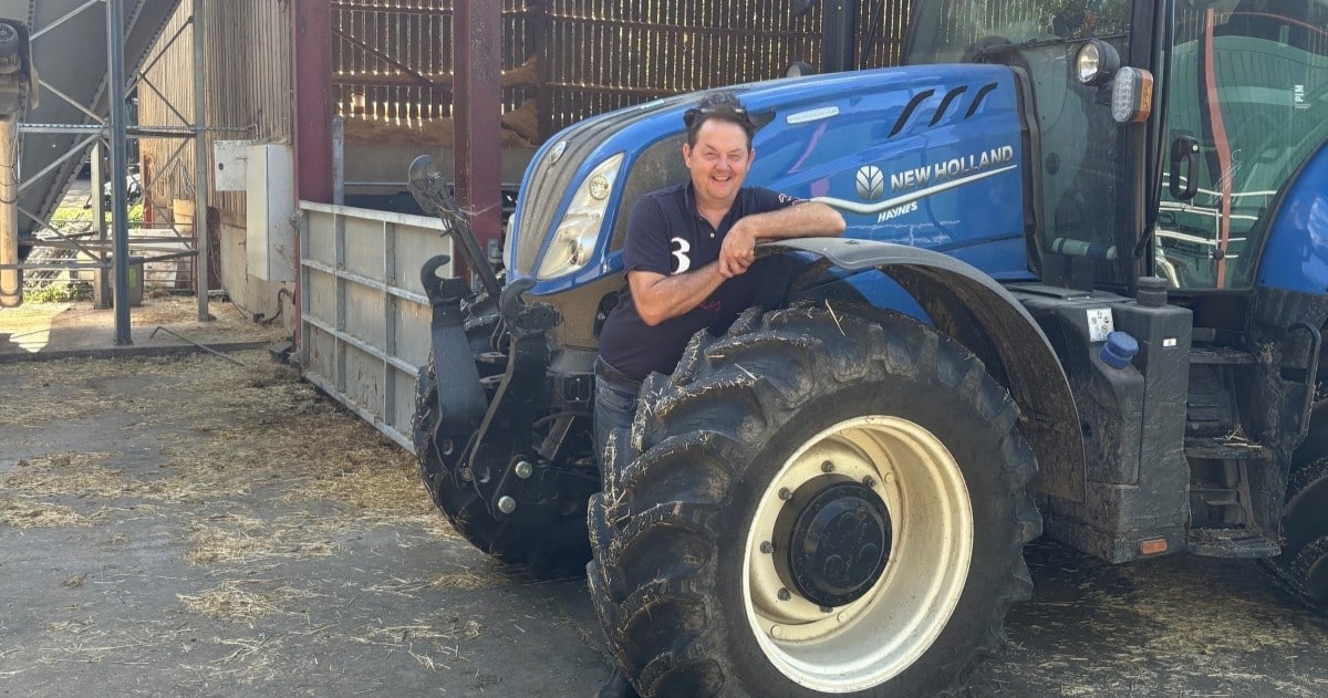 Surrey farmer Hugh Broom next to a blue tractor in his farm yard